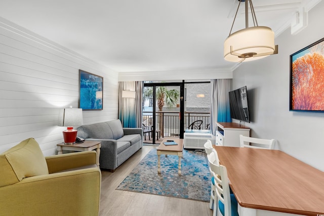 living room featuring wood walls, light hardwood / wood-style floors, and crown molding