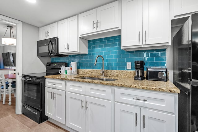 kitchen featuring white cabinets, light hardwood / wood-style flooring, light stone counters, sink, and black appliances