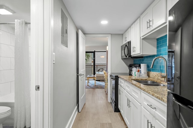 kitchen featuring white cabinetry, black appliances, sink, light stone countertops, and light hardwood / wood-style floors