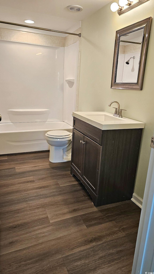 bathroom with visible vents, toilet, washtub / shower combination, vanity, and wood finished floors