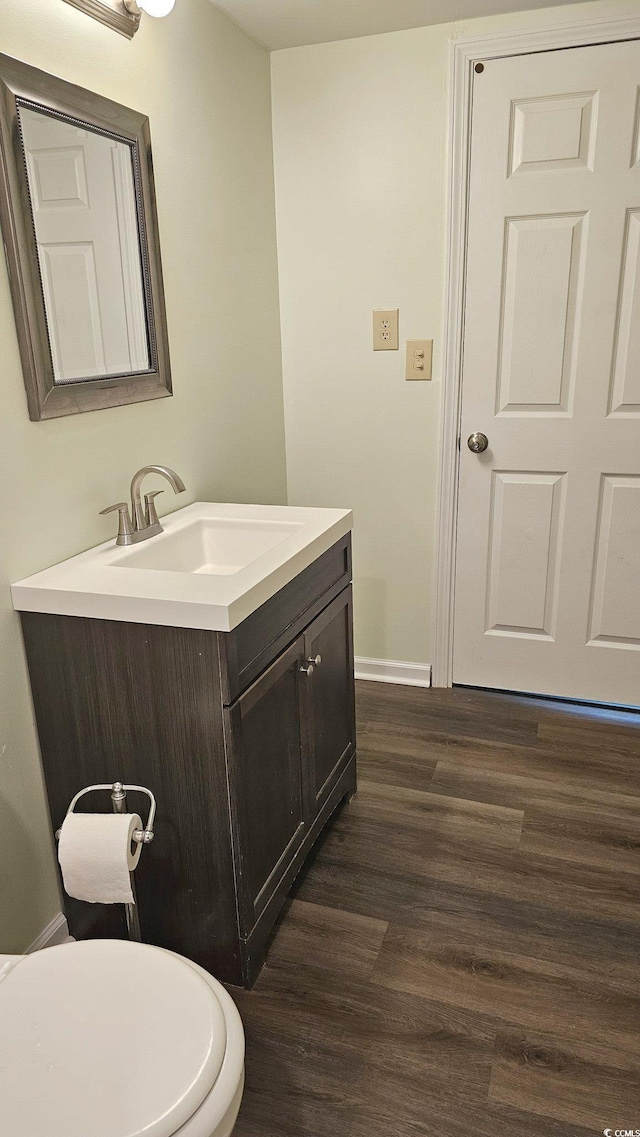 bathroom featuring baseboards, vanity, toilet, and wood finished floors