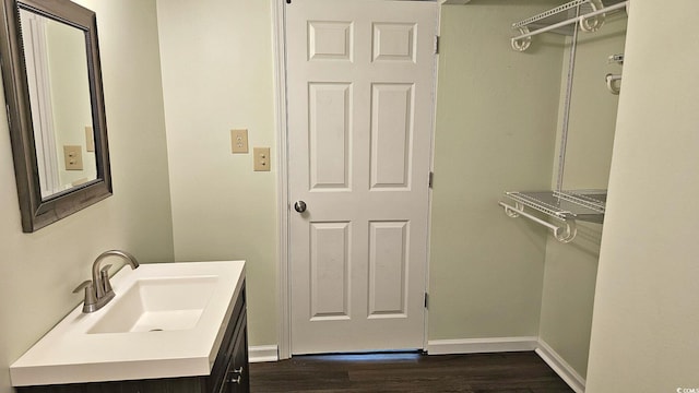 bathroom with wood finished floors, vanity, and baseboards