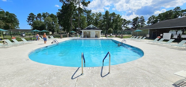 community pool with a patio area and fence