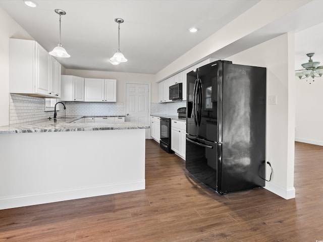 kitchen with light stone counters, hanging light fixtures, white cabinetry, black appliances, and dark hardwood / wood-style floors