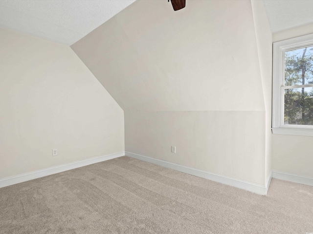 bonus room featuring a textured ceiling, vaulted ceiling, ceiling fan, and light colored carpet