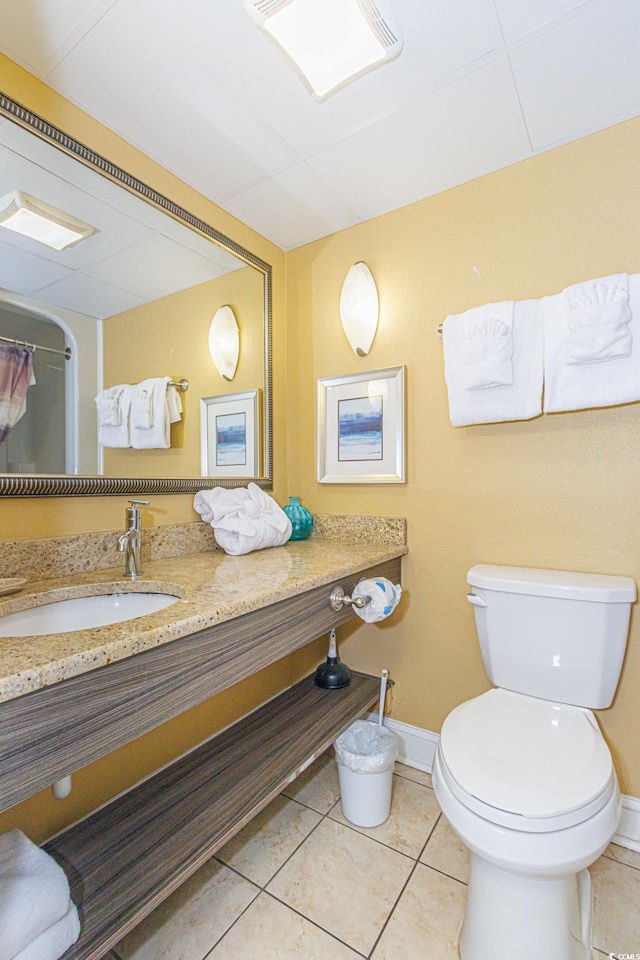 bathroom with tile patterned floors, a paneled ceiling, toilet, and vanity