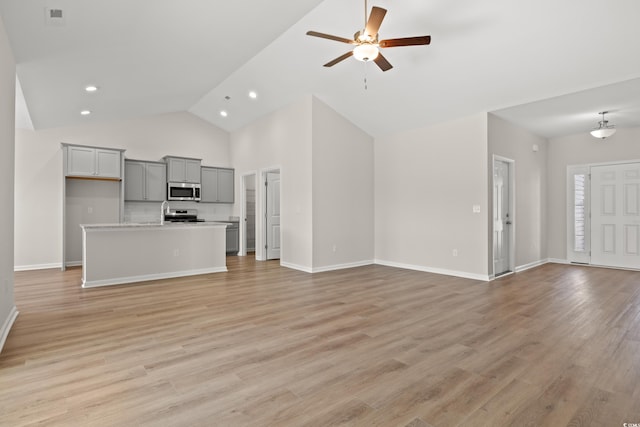 unfurnished living room with ceiling fan, high vaulted ceiling, and light hardwood / wood-style floors