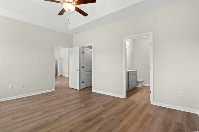 unfurnished bedroom with connected bathroom and light wood-type flooring