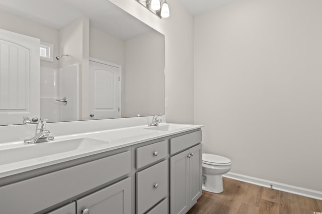 bathroom featuring wood-type flooring, toilet, vanity, and a shower