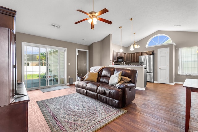 living room with ceiling fan with notable chandelier, high vaulted ceiling, and hardwood / wood-style flooring