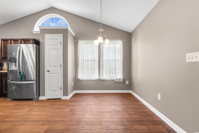 unfurnished dining area with lofted ceiling, an inviting chandelier, and light hardwood / wood-style floors