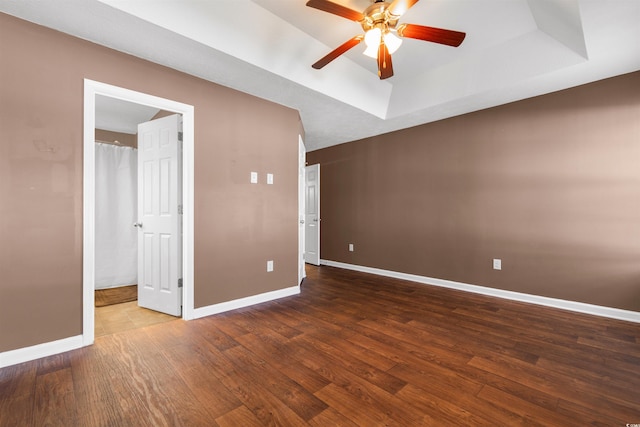 unfurnished room with hardwood / wood-style floors, ceiling fan, and a raised ceiling