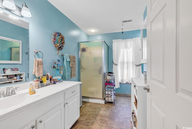 bathroom featuring vanity, a textured ceiling, and a shower with shower door