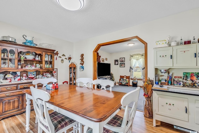 dining space featuring light hardwood / wood-style flooring and a textured ceiling