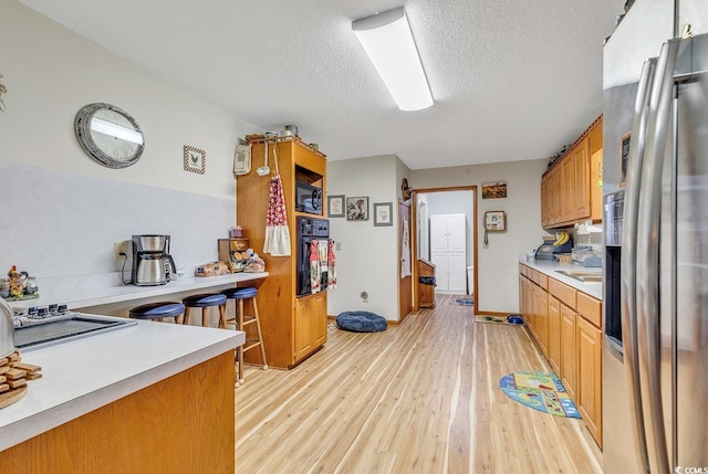 kitchen with black appliances, light hardwood / wood-style floors, and a textured ceiling