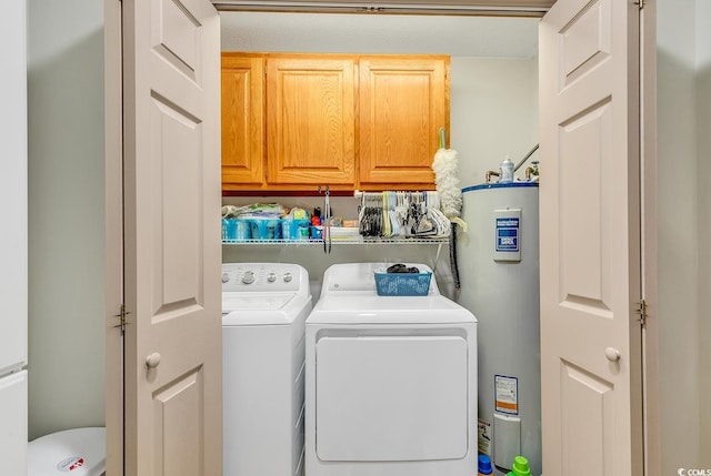 laundry room featuring water heater, washing machine and dryer, and cabinets