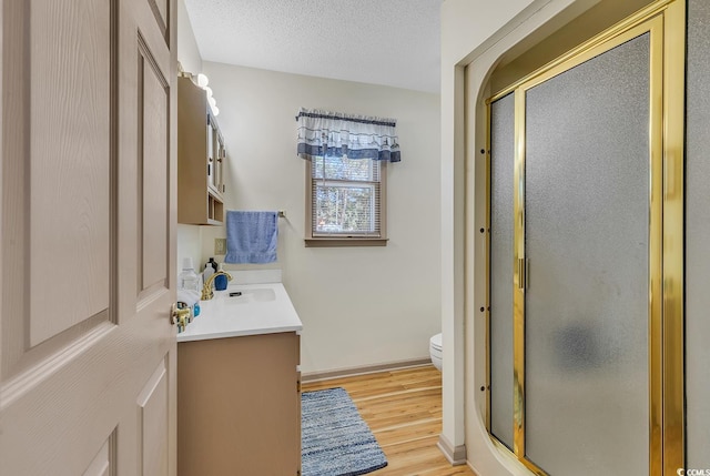 bathroom with hardwood / wood-style flooring, vanity, an enclosed shower, and a textured ceiling