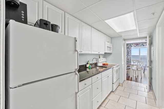 kitchen with white cabinets, sink, white appliances, a drop ceiling, and dark stone counters