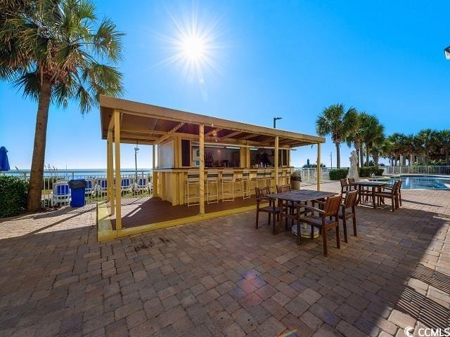 view of patio / terrace with a community pool, exterior bar, and a water view