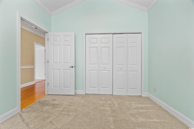 unfurnished bedroom featuring a closet, light colored carpet, crown molding, and vaulted ceiling