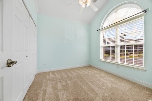 empty room with crown molding, vaulted ceiling, ceiling fan, and carpet floors