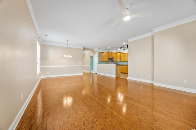 unfurnished living room with light hardwood / wood-style flooring, ornamental molding, and ceiling fan with notable chandelier