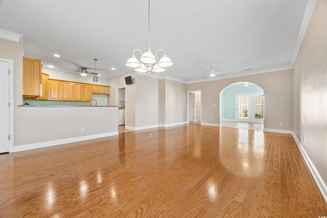 unfurnished living room featuring ceiling fan with notable chandelier, light wood-type flooring, and crown molding