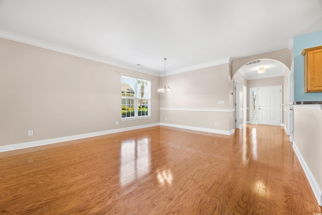 spare room featuring light wood-type flooring, a chandelier, and crown molding