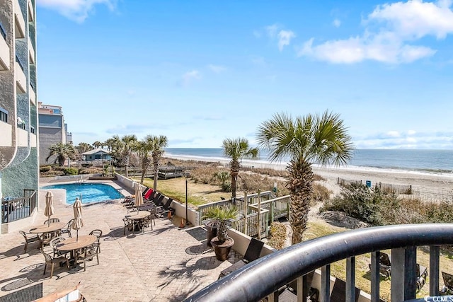 view of yard with a community pool, a beach view, a water view, and a patio