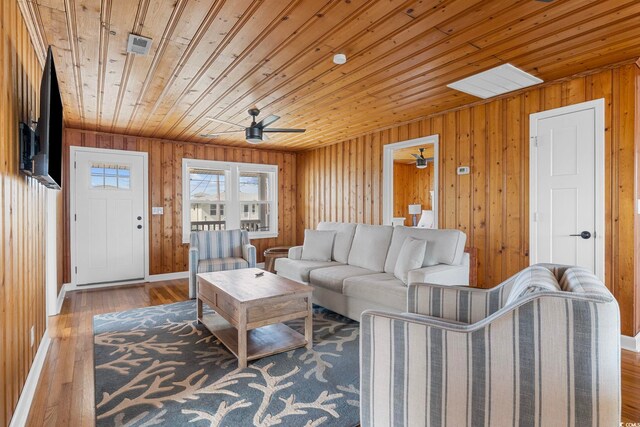 living room with ceiling fan, wood ceiling, hardwood / wood-style flooring, and wood walls