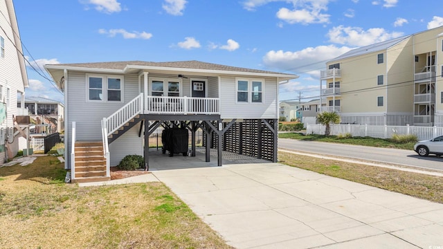 raised beach house featuring covered porch and a carport