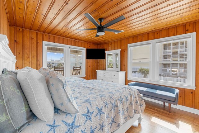 bedroom featuring wood walls, light wood-type flooring, and ceiling fan