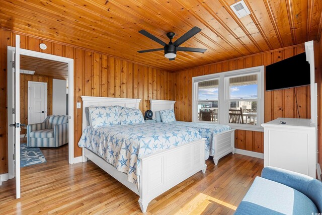 bedroom with wood walls, wooden ceiling, light wood-type flooring, and ceiling fan