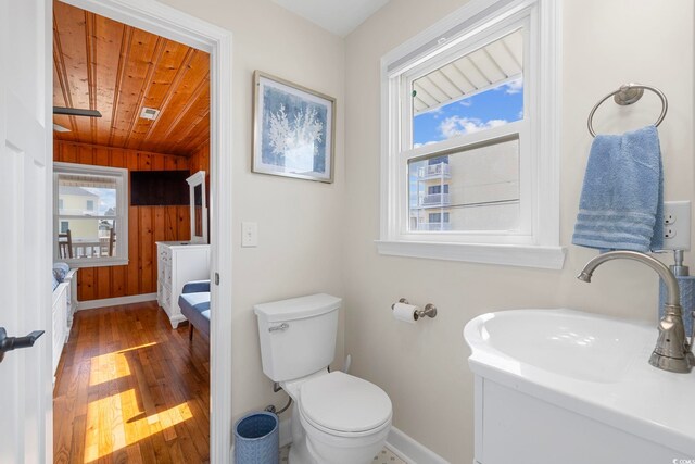 bathroom with sink, toilet, wooden ceiling, wooden walls, and hardwood / wood-style flooring