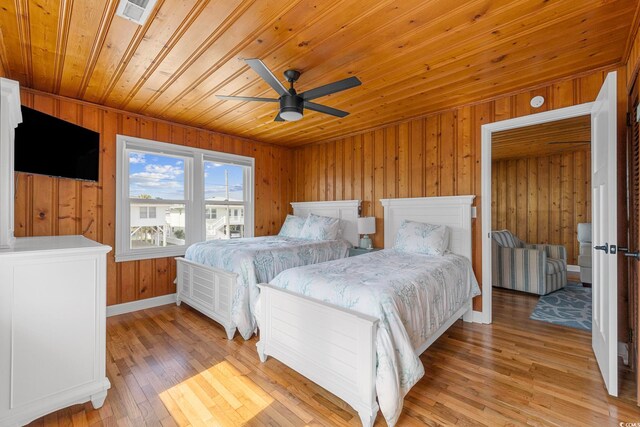 bedroom with wooden walls, light hardwood / wood-style flooring, wooden ceiling, and ceiling fan