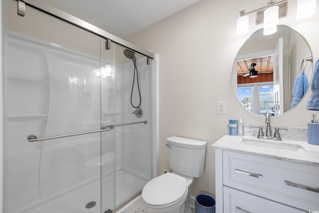 bathroom featuring vanity, toilet, a shower with door, and ceiling fan