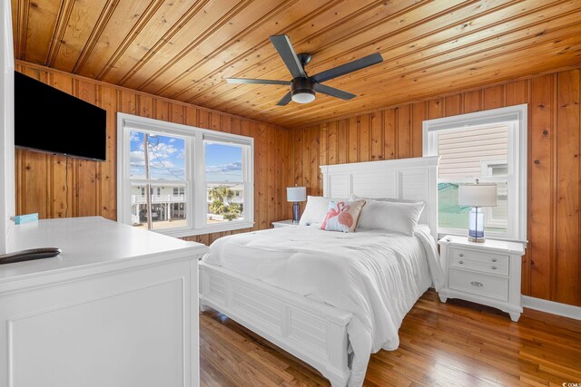 bedroom with wooden walls, hardwood / wood-style flooring, wooden ceiling, and ceiling fan