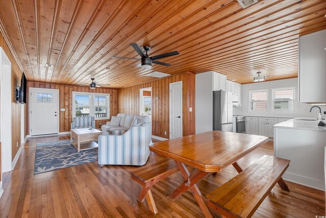 dining room with wood walls, wooden ceiling, wood-type flooring, and plenty of natural light