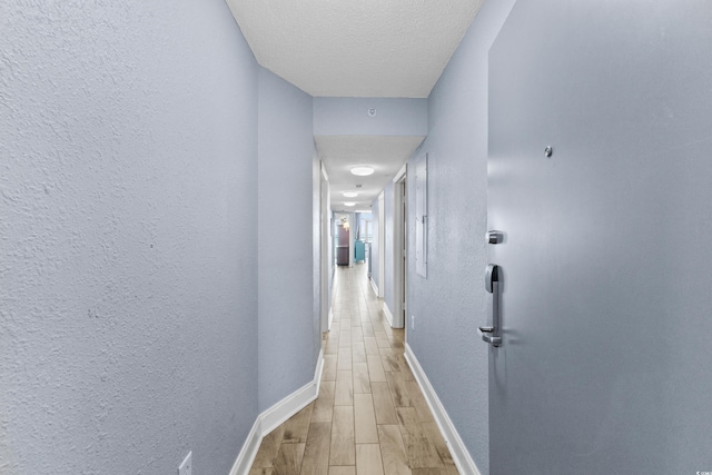 corridor featuring light hardwood / wood-style flooring and a textured ceiling