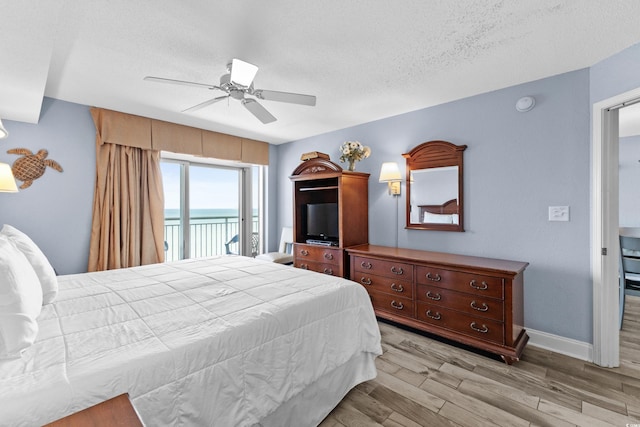 bedroom featuring light hardwood / wood-style floors, ceiling fan, access to outside, and a textured ceiling