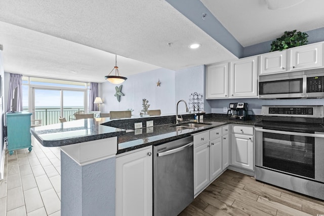 kitchen featuring a textured ceiling, kitchen peninsula, stainless steel appliances, and white cabinets