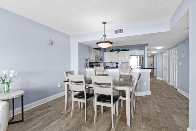 dining room featuring a textured ceiling, wood-type flooring, and sink