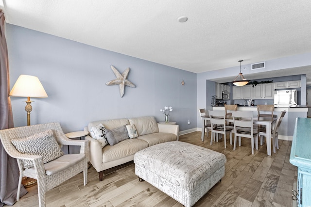 living room featuring a textured ceiling and light wood-type flooring