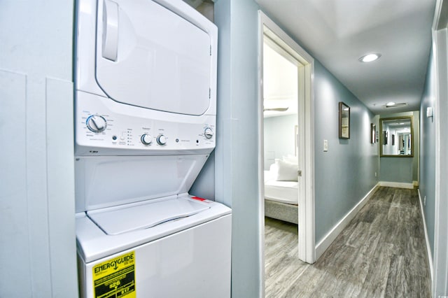 washroom with hardwood / wood-style floors and stacked washer and dryer