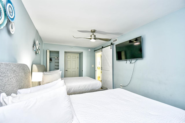 bedroom featuring ceiling fan and a barn door