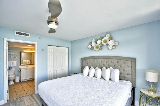 bedroom with ensuite bath, hardwood / wood-style floors, ceiling fan, and a closet