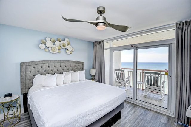 bedroom with access to outside, hardwood / wood-style floors, ceiling fan, and a water view