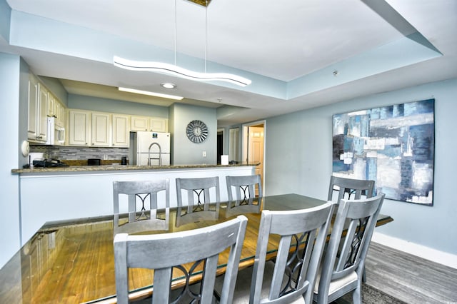 dining area with a raised ceiling and hardwood / wood-style floors