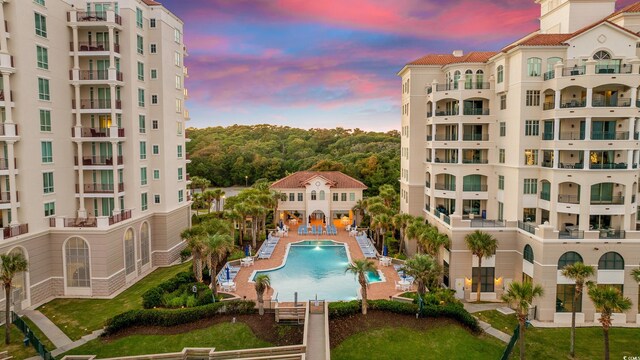 pool at dusk featuring pool water feature