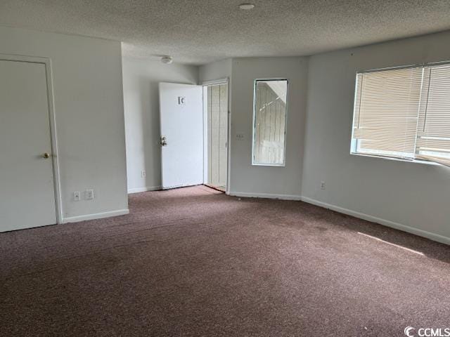 empty room featuring carpet, baseboards, and a textured ceiling